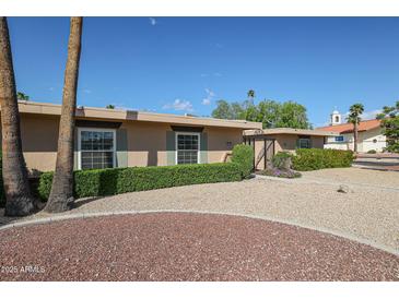 Charming single-story home with manicured landscaping, gravel yard, and view of a church at 17238 N 107Th Ave, Sun City, AZ 85373