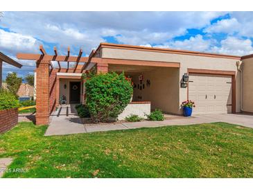 Charming single-story home featuring a well-manicured lawn, brick accents, and a cozy covered porch at 34 Leisure World --, Mesa, AZ 85206