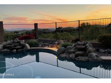 Relaxing pool featuring rock waterfalls with desert landscape views at sunset at 42102 N Long Cove Way, Phoenix, AZ 85086