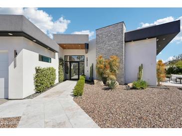 Modern home exterior with desert landscaping, a stone facade, and a sleek design, creating a stylish curb appeal at 4502 E Solano Dr, Phoenix, AZ 85018