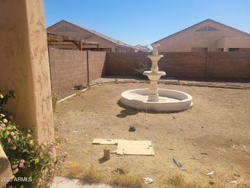 Spacious backyard featuring a decorative fountain, surrounded by a block wall for added privacy at 5665 W Laurie Ln, Glendale, AZ 85302