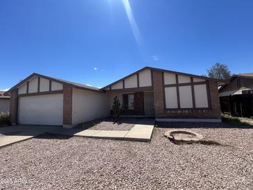 Single-story home with brick accents, a two-car garage, and desert landscaping at 6225 W Zoe Ella Way, Glendale, AZ 85306