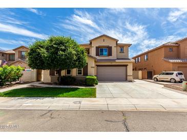 Two-story home featuring desert landscaping, two-car garage, and neutral color scheme under a bright blue sky at 13259 W Flower St, Litchfield Park, AZ 85340