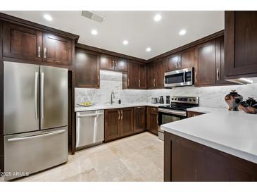 Modern kitchen features stainless steel appliances, dark cabinetry, and bright, tiled backsplash at 15380 N 100Th St # 1124, Scottsdale, AZ 85260