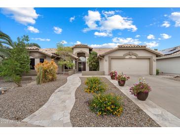Charming home featuring a well-manicured front yard with stone walkway, flowers, and a two-car garage at 8542 W Rosemonte Dr, Peoria, AZ 85382