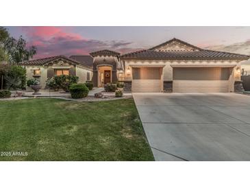 Charming home with three-car garage, desert landscaping, and warm exterior lighting at sunset at 11511 E Chestnut Ct, Chandler, AZ 85249