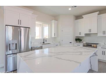Bright kitchen with stainless steel appliances, large island, and white cabinetry at 43481 W Carefree Pl, Maricopa, AZ 85138