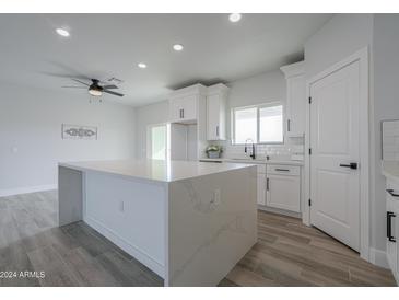 Bright kitchen featuring white cabinets, quartz countertops, a spacious island and modern finishes at 43481 W Carefree Pl, Maricopa, AZ 85138