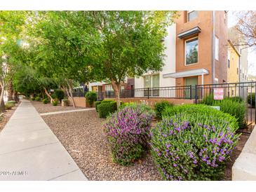 Attractive two-story exterior featuring a well-maintained landscape with mature trees and purple flowering shrubs at 706 E Washington St # 207, Phoenix, AZ 85034