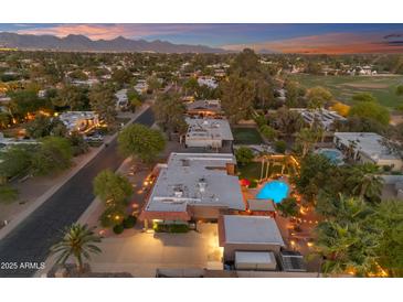 Expansive aerial view showcasing a Scottsdale home with a sparkling pool, lush landscaping, and mountain views at sunset at 5837 E Presidio Rd, Scottsdale, AZ 85254