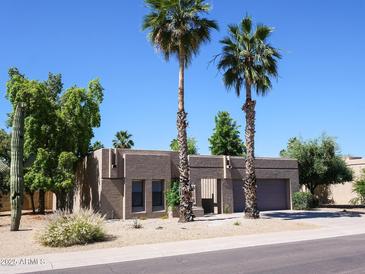 Inviting single-story home featuring palm trees, desert landscaping, and an attached two-car garage at 6721 E Phelps Rd, Scottsdale, AZ 85254
