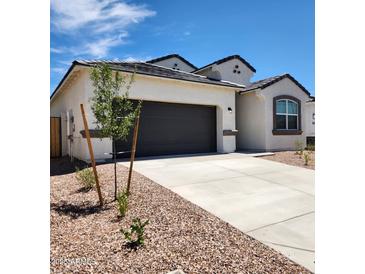 Charming single-story home featuring a gray garage door, neutral stucco and simple desert landscaping at 4939 S 106Th Ave, Tolleson, AZ 85353