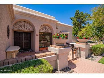 Charming home entrance with decorative ironwork, terracotta tiles, and beautiful potted plants, offering curb appeal at 7315 E Arlington Rd, Scottsdale, AZ 85250