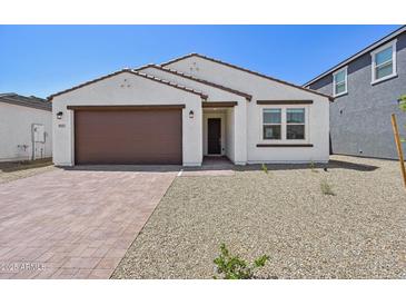 Charming single-story home featuring a brick driveway, a two-car garage, and a low-maintenance desert landscape at 9547 W Parkway Dr, Tolleson, AZ 85353