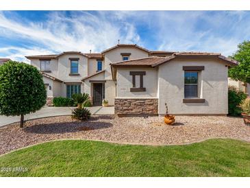 Charming two-story home featuring a landscaped front yard and stylish stone accents and lovely desert landscaping at 15028 W Minnezona Ave, Goodyear, AZ 85395
