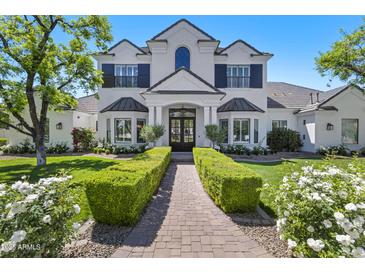 Elegant two-story home featuring a well-manicured lawn, lush greenery, and a charming brick pathway to the front door at 23902 S 202Nd Ct, Queen Creek, AZ 85142
