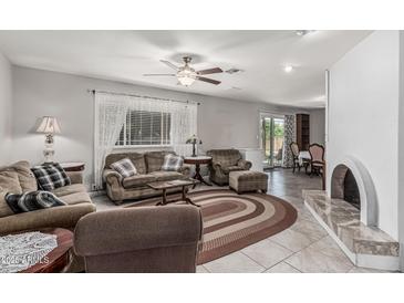 Inviting living room featuring tile floors, a ceiling fan, a fireplace, and comfortable seating arrangements at 6055 E Hannibal St, Mesa, AZ 85205