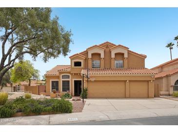 Two-story home featuring a three-car garage, a well-maintained yard, and a terracotta roof in a suburban neighborhood at 6901 W Tonto Dr, Glendale, AZ 85308
