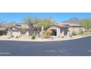 Stunning single-story home featuring a two-car garage, solar panels, desert landscaping, and mountain views at 10694 E Firethorn Dr, Scottsdale, AZ 85255