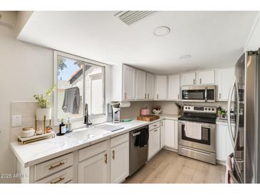 Bright kitchen features stainless steel appliances, white cabinetry, and a marble-look countertop at 5350 N 3Rd Ave, Phoenix, AZ 85013
