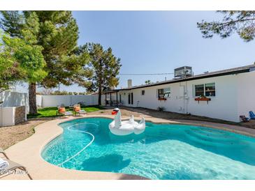 Inviting backyard pool with a large inflatable swan, lounge chairs and a well-manicured lawn at 8220 E Crestwood Way, Scottsdale, AZ 85250