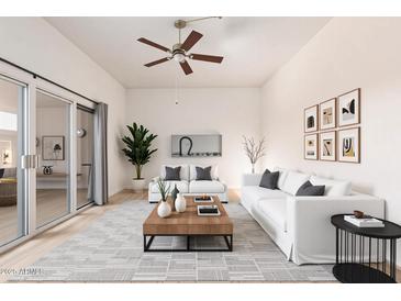 Bright living room with modern furniture, ceiling fan, light wood floors, and sliding glass doors to outdoor space at 13821 N Thunderbird Blvd, Sun City, AZ 85351