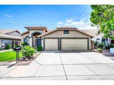 Charming home with a two-car garage, tiled roof, and a well-manicured front yard at 1835 E Marquette Dr, Gilbert, AZ 85234