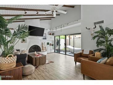 Bright living room boasts vaulted ceilings, wood beams, tiled fireplace, and sliding glass doors to a private patio at 2839 N 61St St, Scottsdale, AZ 85257