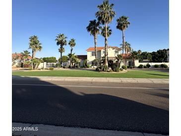Charming two-story home featuring lush landscaping, a well-manicured lawn, and elegant curb appeal with mature palm trees at 6337 W Deer Valley Rd, Glendale, AZ 85308