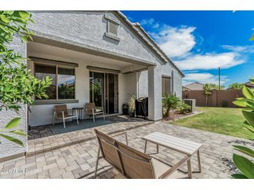 The backyard patio features seating and a grill with a view of the well-maintained lawn and blue sky at 14419 W El Cortez Pl, Surprise, AZ 85387