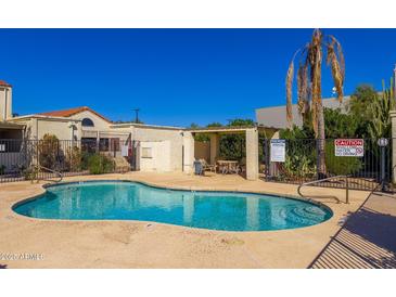 Community pool area featuring a clear blue pool, a shaded seating area, and desert landscaping under a bright blue sky at 15801 N 29Th St # 16, Phoenix, AZ 85032