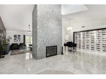 Spacious living room with tiled floors, fireplace, piano and a wine rack is great for entertaining at 102 S Honeysuckle Ln, Gilbert, AZ 85296