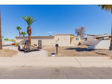 Charming single-story home featuring desert landscaping and mature palm trees for a tranquil outdoor setting at 10472 W Devonshire Ave, Phoenix, AZ 85037