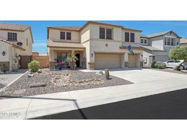 Two-story stucco home featuring a three-car garage, desert landscaping, and covered front porch at 30185 W Flower St, Buckeye, AZ 85396