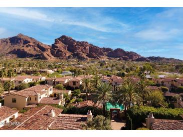 Stunning aerial view of the community with red tile roofs, palm trees, and a mountain backdrop on a sunny day at 4949 E Lincoln Dr # 11, Paradise Valley, AZ 85253