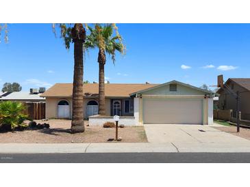 Charming single-story home with a two-car garage and palm trees in the front yard, under a clear blue sky at 7506 W Devonshire Ave, Phoenix, AZ 85033