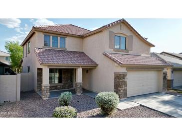 Charming two-story home with a well-manicured front yard and inviting front porch, stone accents, and tile roof at 10031 W Hess St, Tolleson, AZ 85353