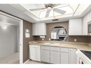 Bright kitchen features white cabinetry, a cozy pass-through window, and laminate countertops at 1217 N Miller Rd # 32, Scottsdale, AZ 85257