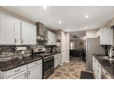 Updated kitchen with modern stainless steel appliances and tiled backsplash, adjacent to a cozy living area at 18016 N 145Th Ave, Surprise, AZ 85374