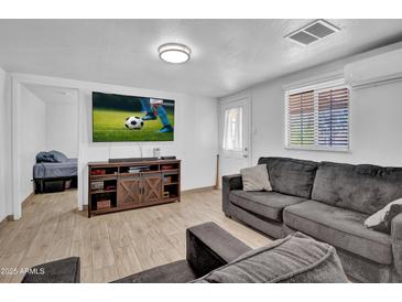 Cozy living room with a comfortable gray sofa, entertainment center, and bright natural light at 1815 E Illini St, Phoenix, AZ 85040