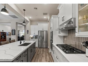 Bright kitchen with white cabinetry, a gas range, stainless steel appliances, and an island at 1906 N 140Th Dr, Goodyear, AZ 85395