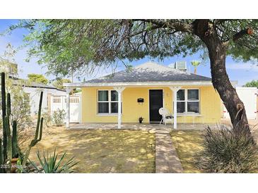 Charming yellow home featuring a covered front porch, well-kept yard, and mature tree at 227 N Morris --, Mesa, AZ 85201