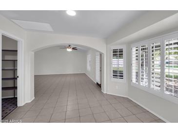 Open-concept living room with neutral color palette, tile flooring, and plenty of natural light through plantation shutters at 20042 W Dunlap Rd, Buckeye, AZ 85326