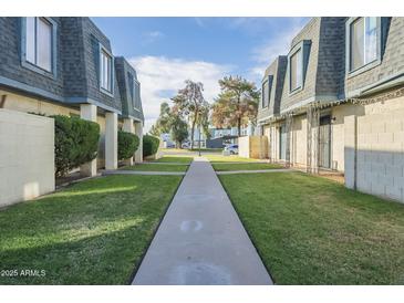 A peaceful community with lush green lawns and well-maintained townhomes under a bright blue sky at 3222 W Royal Palm Rd, Phoenix, AZ 85051