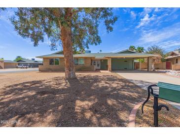 Charming single-story brick home featuring a carport and mature shade tree in the front yard under a sunny blue sky at 7126 N 29Th Dr, Phoenix, AZ 85051