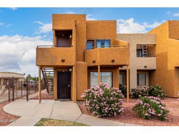 Inviting two-story exterior showcases a private balcony, decorative rock and lush flowering bushes at 11640 N 51St Ave # 211, Glendale, AZ 85304