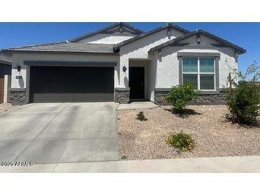 Charming single-story home featuring a neutral color scheme, a two-car garage, and a well-maintained, low-water, xeriscaped front yard at 17755 W Onyx Ave, Waddell, AZ 85355