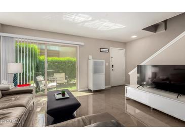 Bright living room with a modern entertainment center and sliding door access to a charming outdoor patio at 4600 N 68Th St # 302, Scottsdale, AZ 85251