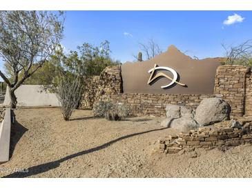 Scenic community entrance featuring stacked stone walls and desert landscaping under a clear blue sky at 10040 E Happy Valley Rd # 2058, Scottsdale, AZ 85255