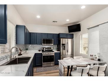 Modern kitchen features navy cabinets, stainless steel appliances, white countertops and a dining table at 10239 W Via Del Sol -- # 400, Peoria, AZ 85383